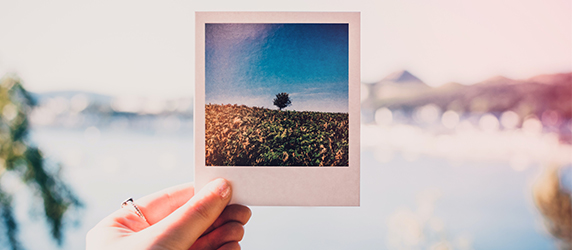 Iemand die een polaroid foto in zijn hand houdt