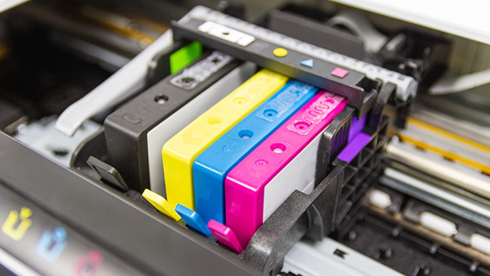 Hoe bewaar ik mijn inktcartridges Afbeelding van alle kleuren inktcartridges in een printer